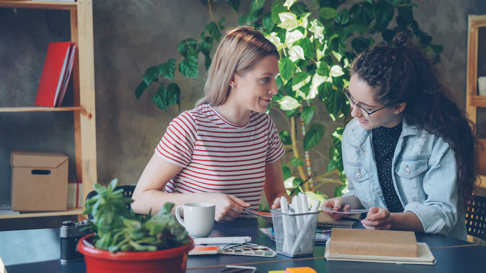 Duas mulheres a estudar juntas a uma mesa com plantas